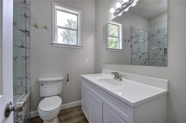 full bath with plenty of natural light, a tile shower, wood finished floors, and baseboards
