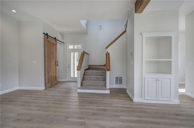 foyer entrance with a barn door, stairs, baseboards, wood finished floors, and recessed lighting
