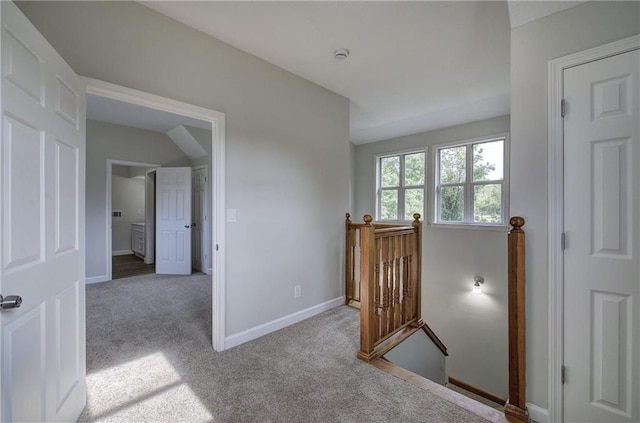 hall with an upstairs landing, carpet, and baseboards