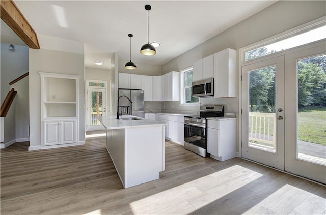 kitchen with appliances with stainless steel finishes, light wood-style floors, french doors, white cabinetry, and light countertops