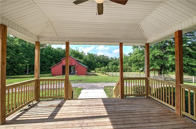 wooden deck featuring ceiling fan, view of wooded area, an outbuilding, and a barn