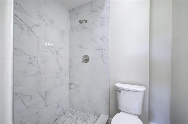 bathroom featuring a tile shower and toilet