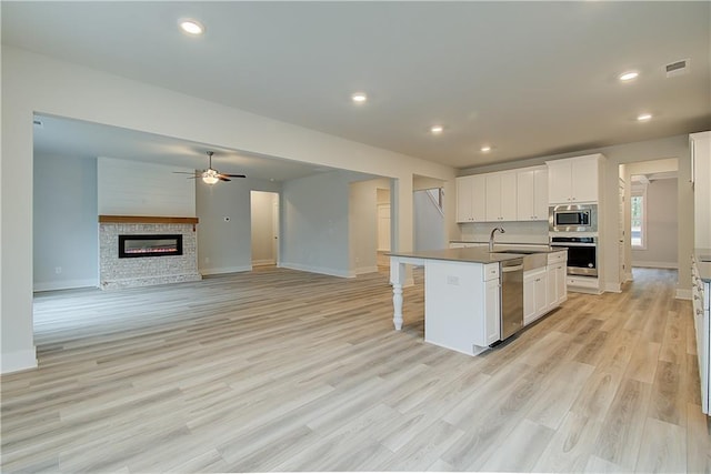 kitchen featuring a center island with sink, white cabinets, light hardwood / wood-style flooring, and appliances with stainless steel finishes