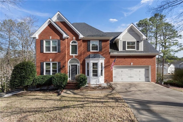 colonial inspired home with a garage, a shingled roof, concrete driveway, and brick siding