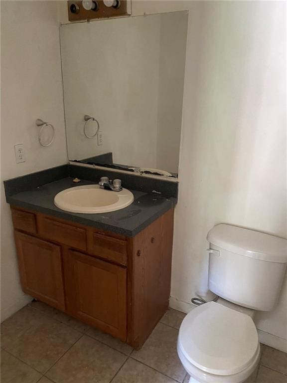 bathroom featuring toilet, tile floors, and vanity