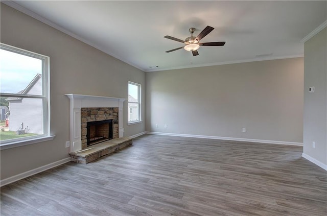 unfurnished living room featuring a stone fireplace, ornamental molding, ceiling fan, and hardwood / wood-style flooring