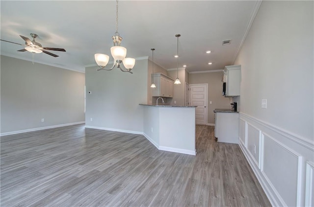 kitchen with sink, decorative light fixtures, ornamental molding, and white cabinets