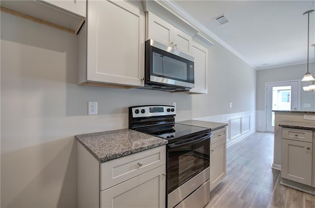 kitchen with stone countertops, pendant lighting, white cabinetry, stainless steel appliances, and crown molding