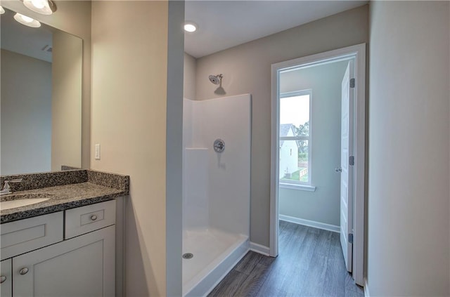 bathroom with walk in shower, vanity, and hardwood / wood-style flooring