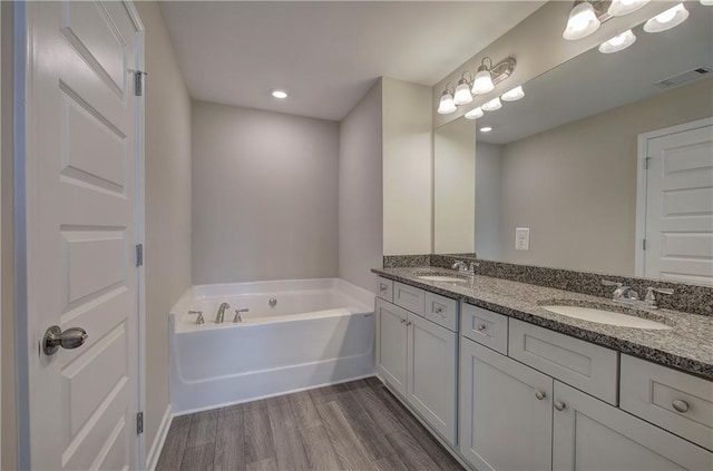 bathroom with a washtub, hardwood / wood-style floors, and vanity