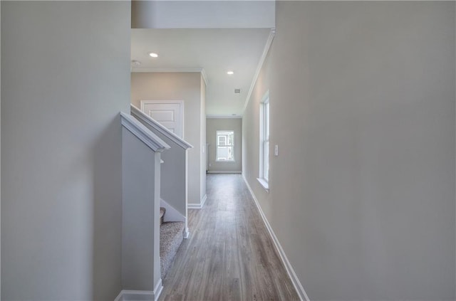 hallway with ornamental molding and light hardwood / wood-style floors