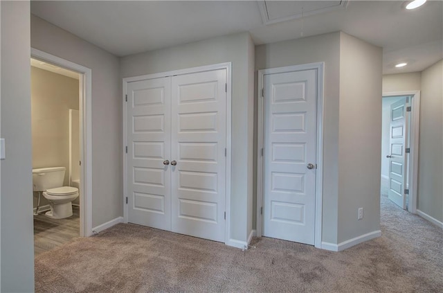 unfurnished bedroom featuring a closet, connected bathroom, and light carpet