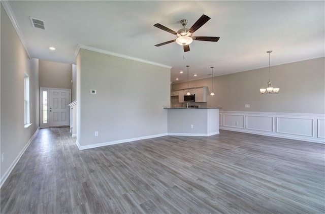 unfurnished living room with crown molding, ceiling fan with notable chandelier, and dark hardwood / wood-style floors