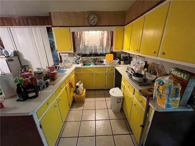 kitchen with light tile patterned floors, light countertops, yellow cabinets, and a sink