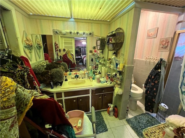 bathroom with toilet, wooden walls, tile patterned flooring, wood ceiling, and vanity