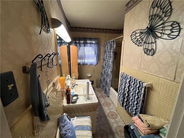 full bath featuring vanity, wallpapered walls, shower / bath combo, wainscoting, and tile walls