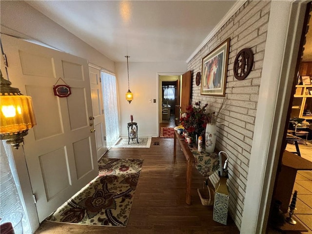 corridor featuring dark wood finished floors and brick wall