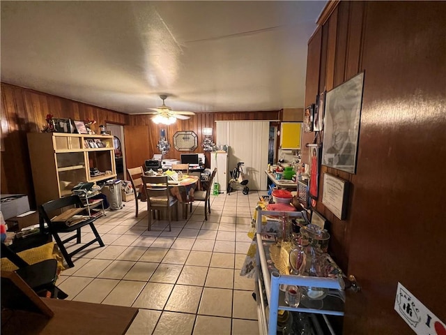 dining space featuring light tile patterned floors, ceiling fan, and wood walls