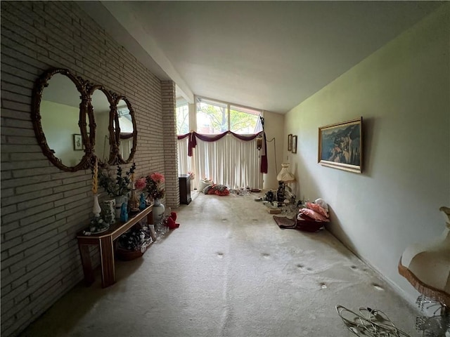 interior space featuring vaulted ceiling, brick wall, and carpet floors