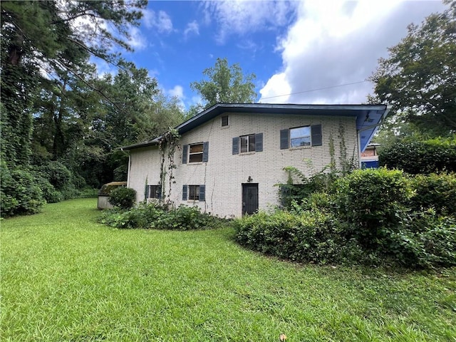 view of side of property featuring a yard and brick siding