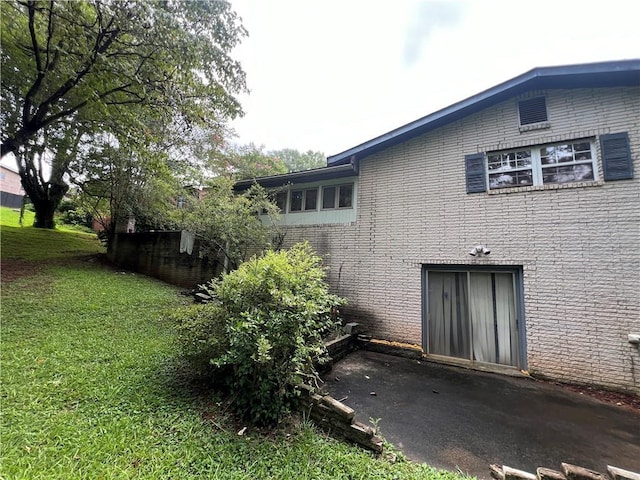 view of property exterior featuring brick siding and a lawn