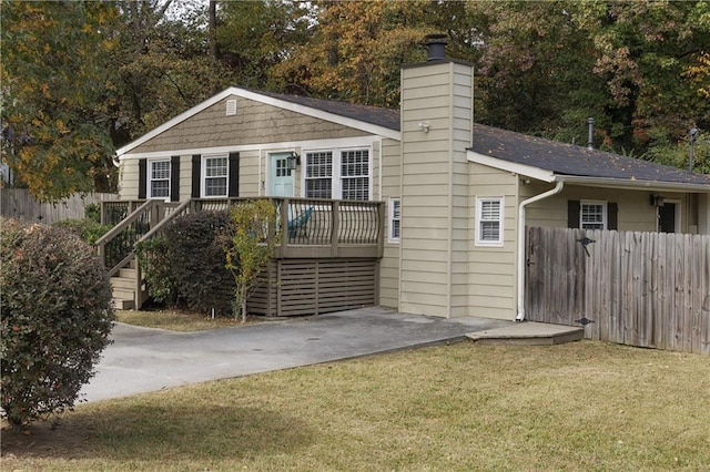 view of front of home with a front lawn, a wooden deck, fence, and a chimney