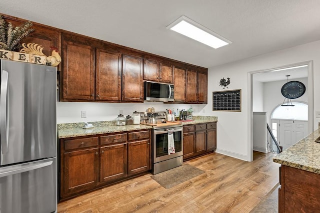 1464 Fieldstone Ct, Winder, GA 30680 - kitchen with stainless steel appliances, light wood-type flooring, light stone counters, and dark brown cabinetry