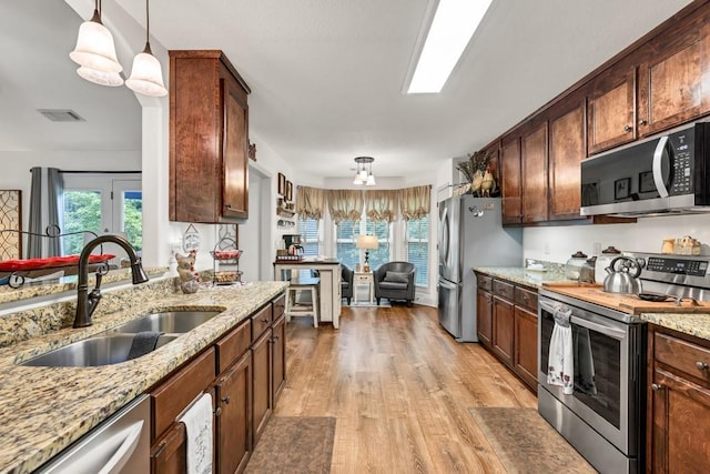1464 Fieldstone Ct, Winder, GA 30680 - kitchen with appliances with stainless steel finishes, light wood-style floors, decorative light fixtures, and light stone counters