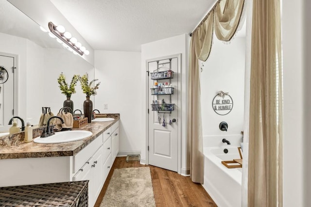 1464 Fieldstone Ct, Winder, GA 30680 - bathroom with wood finished floors, double vanity, shower / bathtub combination with curtain, and a textured ceiling