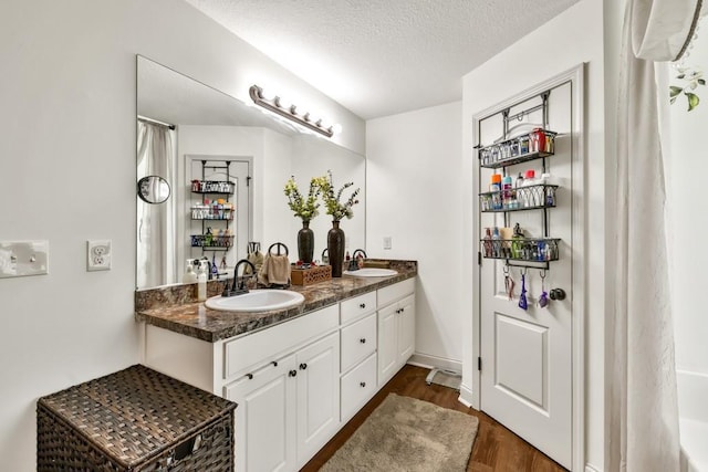 1464 Fieldstone Ct, Winder, GA 30680 - full bathroom with double vanity, wood finished floors, and a textured ceiling