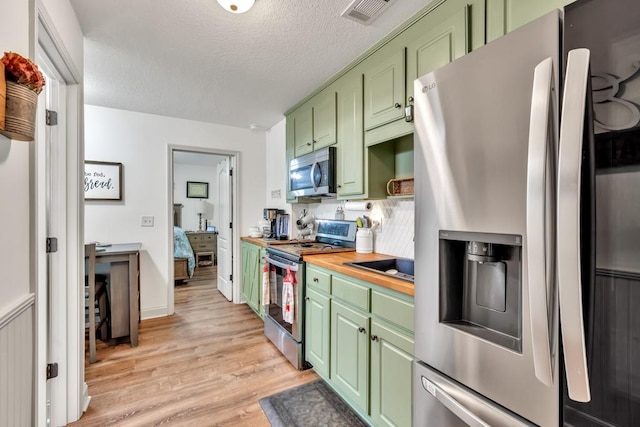 1464 Fieldstone Ct, Winder, GA 30680 - kitchen with stainless steel appliances, green cabinets, light wood-type flooring, a textured ceiling, and wooden counters