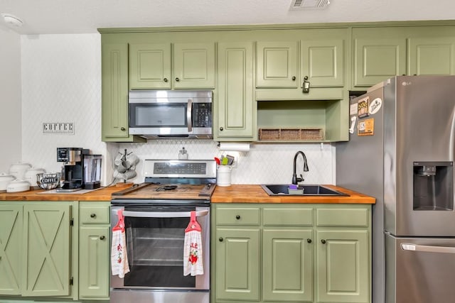 1464 Fieldstone Ct, Winder, GA 30680 - kitchen featuring stainless steel appliances, butcher block counters, green cabinetry, and decorative backsplash