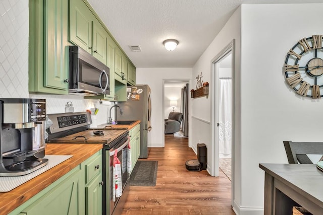 1464 Fieldstone Ct, Winder, GA 30680 - kitchen featuring stainless steel appliances, green cabinetry, wood finished floors, butcher block countertops, and a textured ceiling