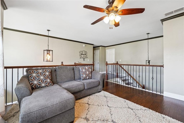living area featuring wood finished floors, a ceiling fan, baseboards, and crown molding