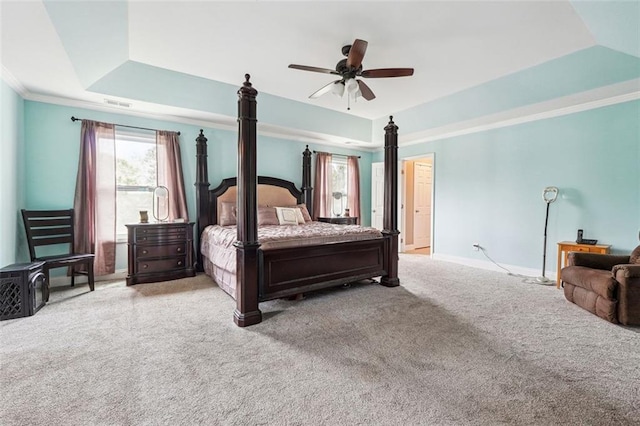 carpeted bedroom with a raised ceiling, baseboards, a ceiling fan, and ornamental molding