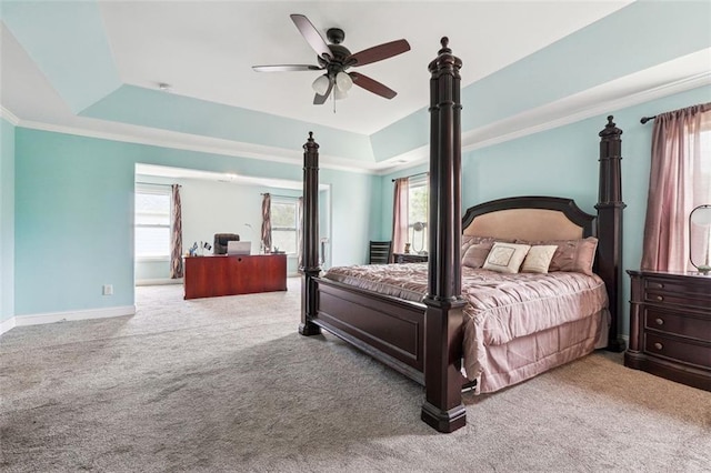 bedroom featuring a raised ceiling, carpet floors, baseboards, ceiling fan, and ornamental molding