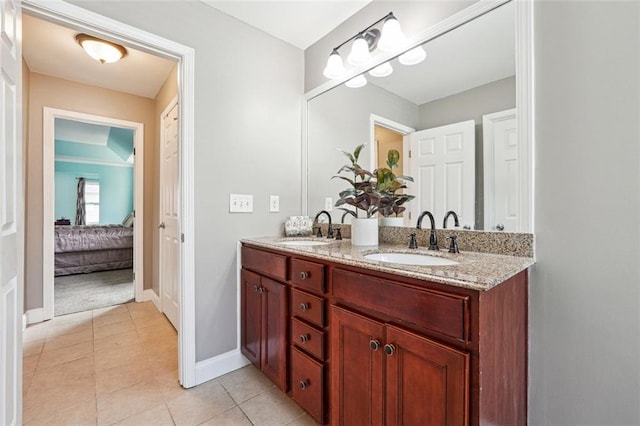 ensuite bathroom featuring double vanity, tile patterned flooring, and baseboards