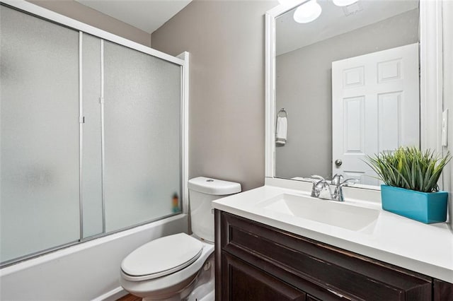 full bath with toilet, vanity, and shower / bath combination with glass door