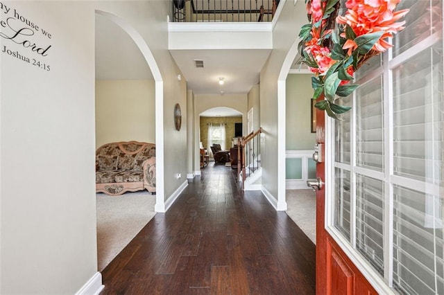 foyer entrance with arched walkways, hardwood / wood-style floors, baseboards, and stairway