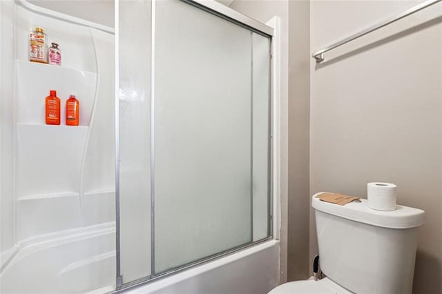 bathroom featuring toilet and combined bath / shower with glass door