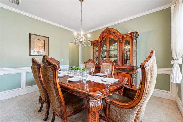 dining area with a chandelier, carpet floors, ornamental molding, and a wainscoted wall