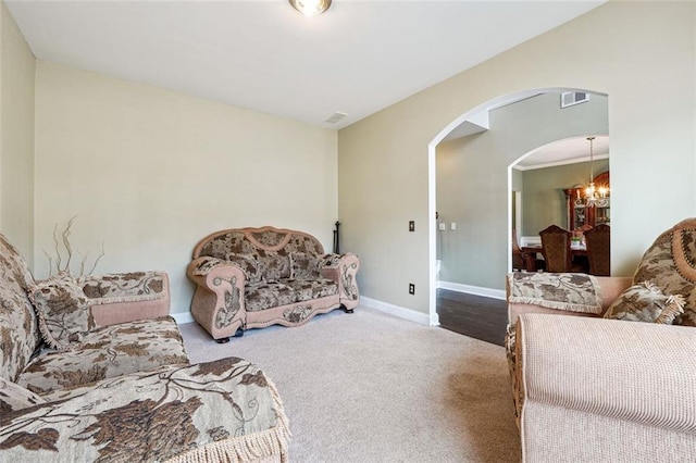 living room featuring arched walkways, a chandelier, carpet, and baseboards