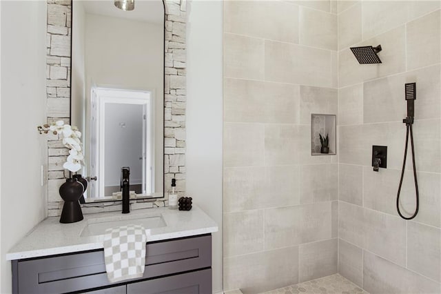 bathroom featuring tiled shower and vanity