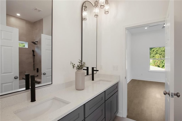 bathroom with tiled shower, vanity, and wood-type flooring