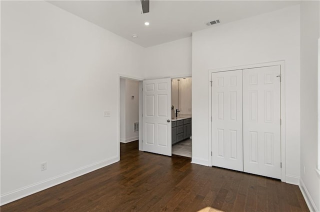 unfurnished bedroom featuring sink, connected bathroom, ceiling fan, a closet, and dark hardwood / wood-style flooring