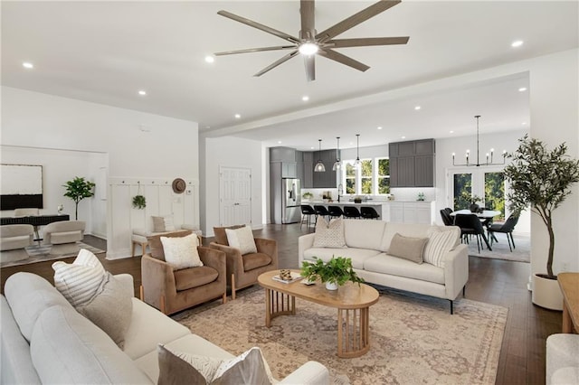 living room with ceiling fan with notable chandelier, beamed ceiling, and hardwood / wood-style floors