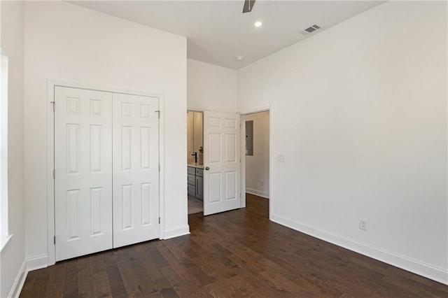 unfurnished bedroom featuring electric panel, dark wood-type flooring, ceiling fan, and a closet