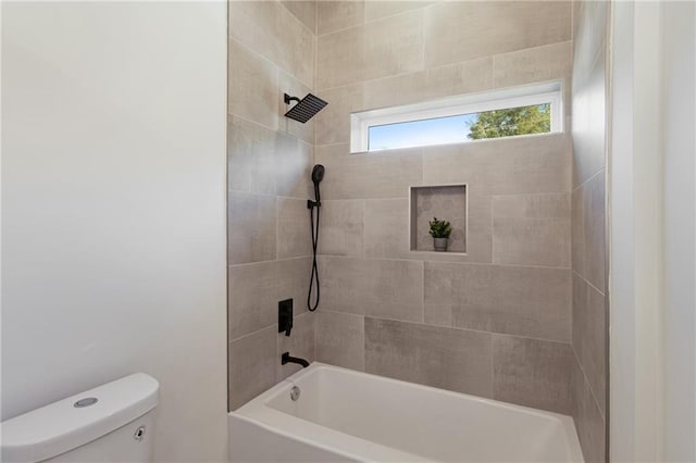 bathroom featuring tiled shower / bath combo and toilet