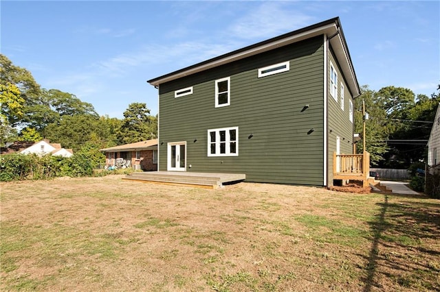 rear view of house featuring french doors, a deck, and a lawn