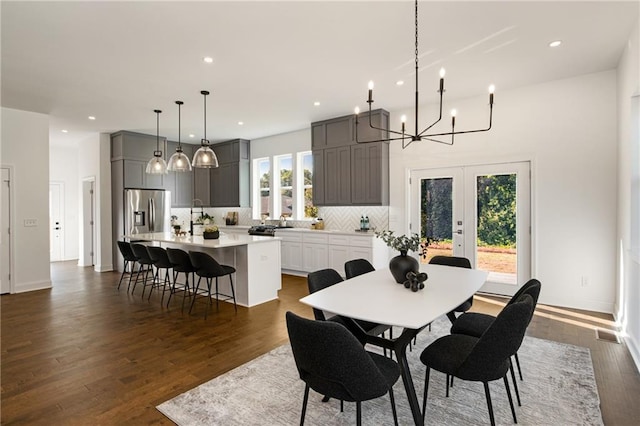 dining room with dark wood-type flooring, an inviting chandelier, french doors, and sink